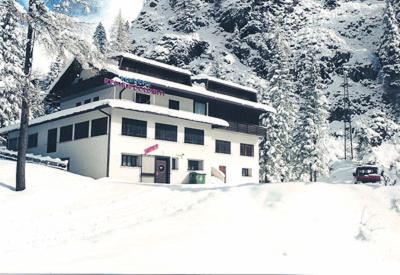 un edificio en la nieve frente a una montaña en Residence Regina Delle Dolomiti, en Rocca Pietore