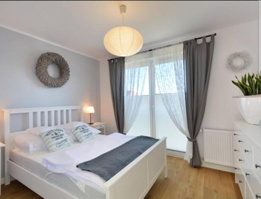 een slaapkamer met een wit bed en een groot raam bij Apartamenty "u Jasia" I in Darlowko