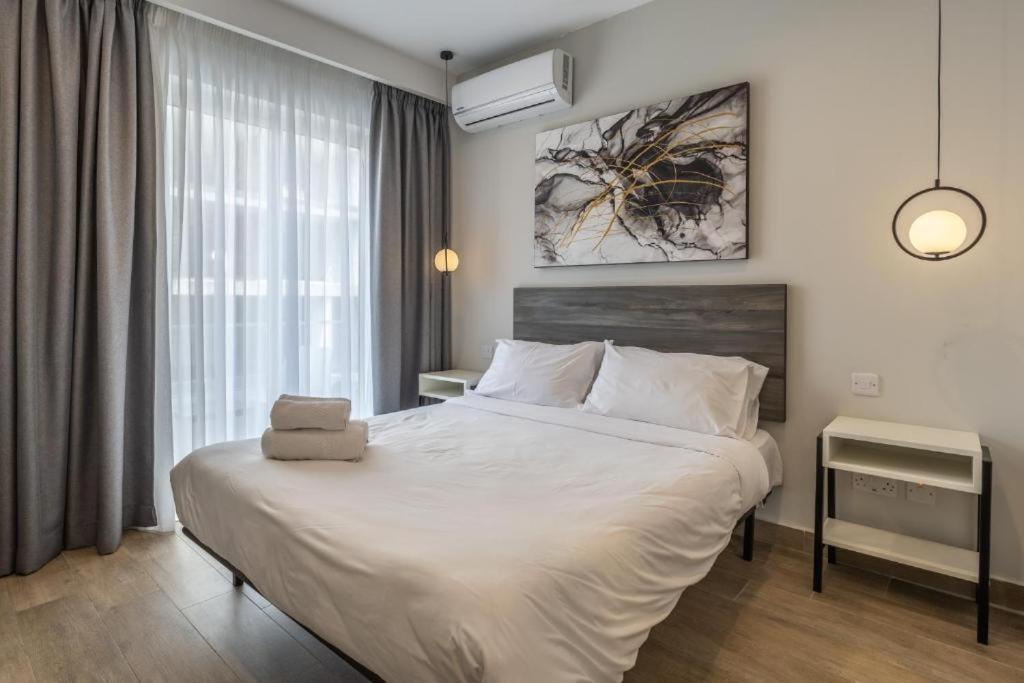 a bedroom with a large white bed in a room at Studio 33 with twin beds & kitchenette at the new Olo living in Paceville