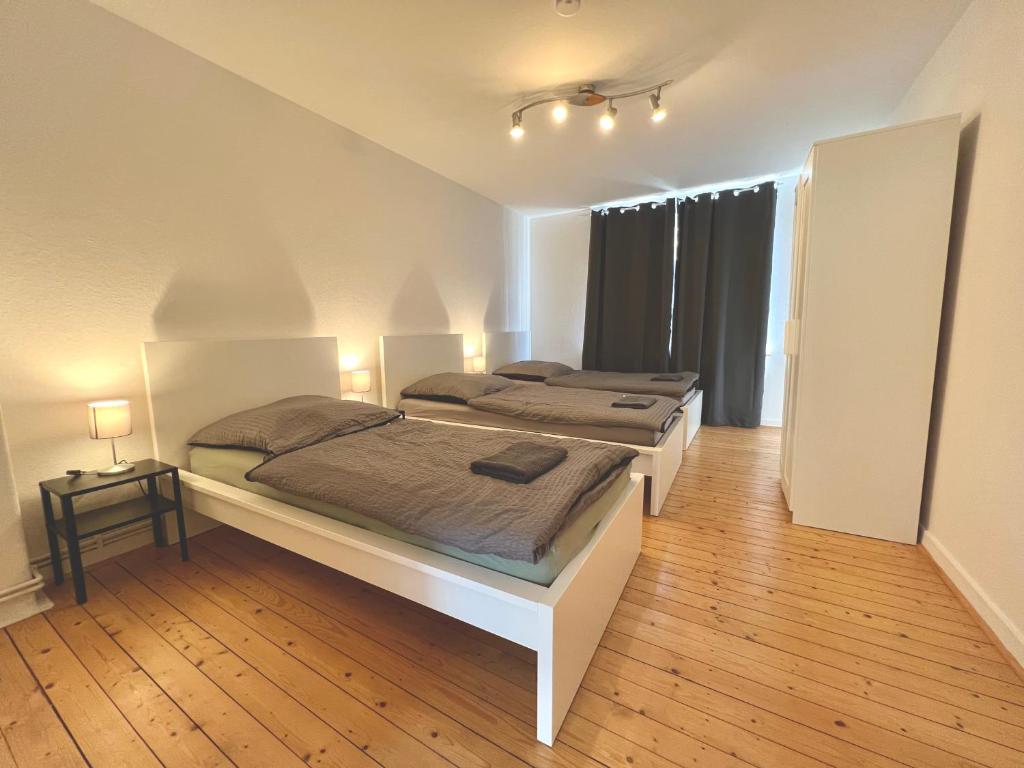 Habitación con suelo de madera y 2 camas. en 3 Betten Unterkunft Vahrenwald-List en Hannover