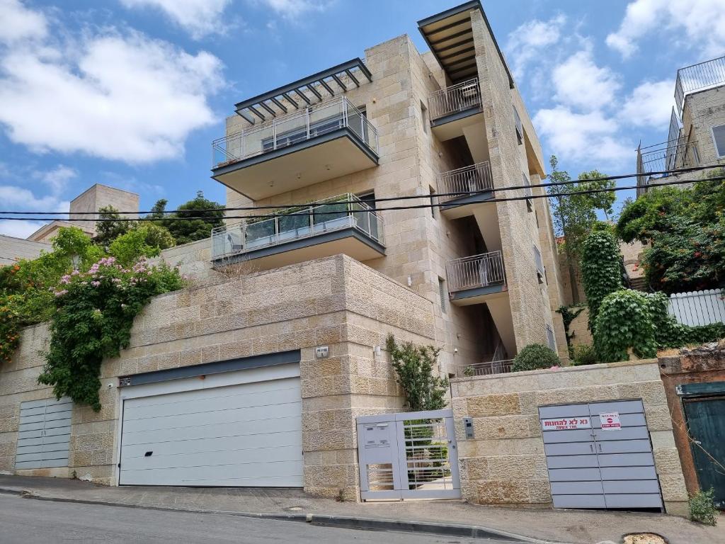 an apartment building with two garage doors and a balcony at Cute Studio near Yad Vashem FREE street parking in Jerusalem
