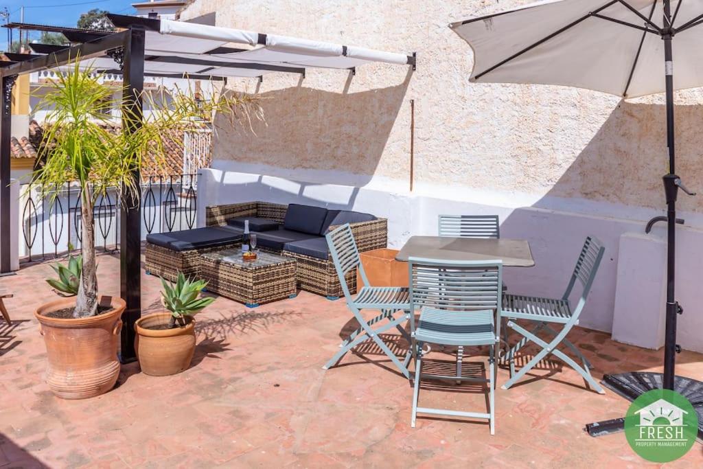eine Terrasse mit einem Tisch, Stühlen und einem Sonnenschirm in der Unterkunft Town house with roof terrace in heart of Vinuela in Viñuela