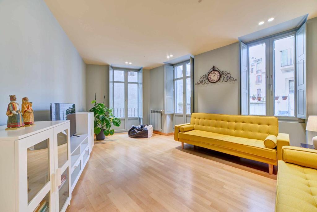 uma sala de estar com um sofá amarelo e janelas em Apartamento El Rincón del Chupinazo em Pamplona
