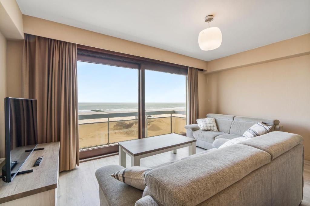 ein Wohnzimmer mit Couch und großem Fenster in der Unterkunft Ster der Zee - zeedijk app voor 6pers met zeezicht in Middelkerke