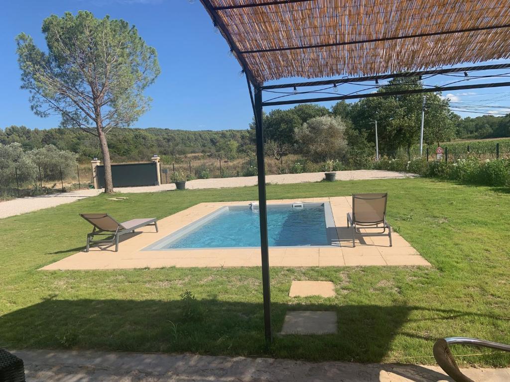 een zwembad met twee stoelen en een rieten dak bij Provencelia in Pernes-les-Fontaines