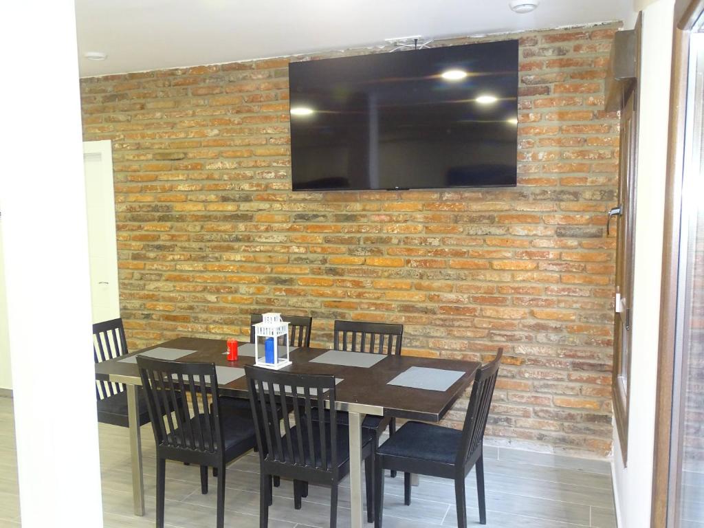 a table with chairs and a television on a brick wall at Albergue Roma in Pola de Lena