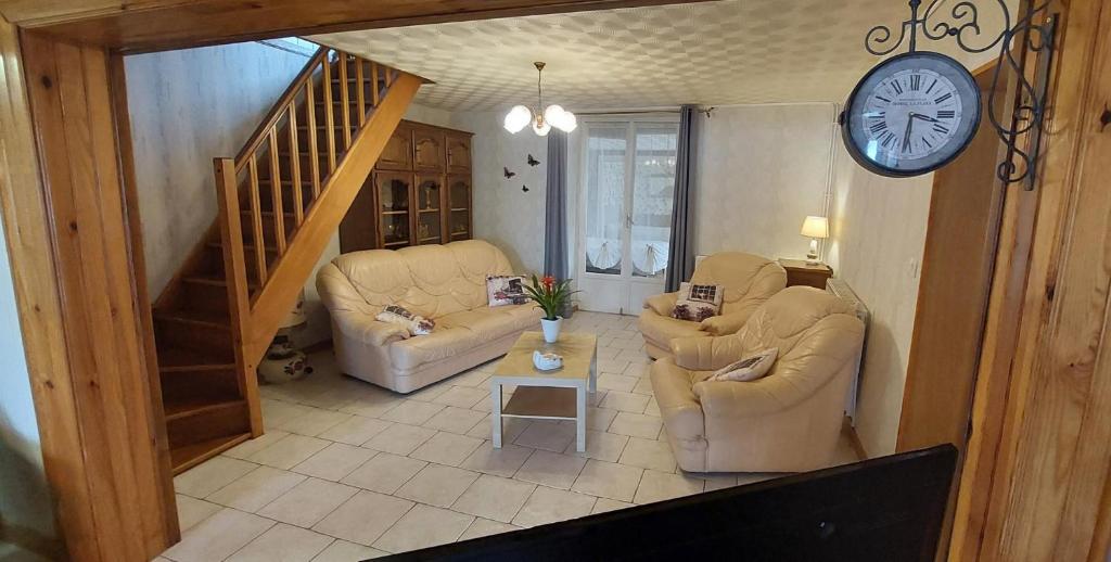 a living room with two chairs and a clock on the wall at Chez marcelle in Éteignières