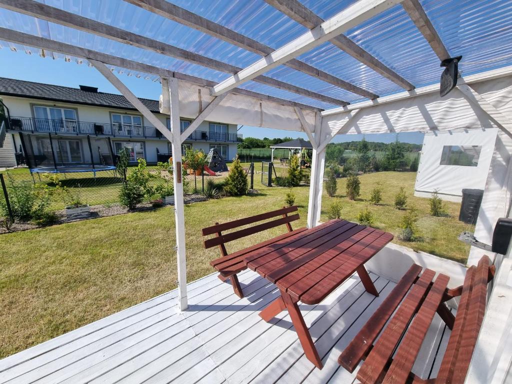 a wooden picnic table and bench on a deck at 365PAM - Domek Letniskowy Kolory Lata - Z KLIMATYZACJĄ I PARKINGIEM in Sarbinowo