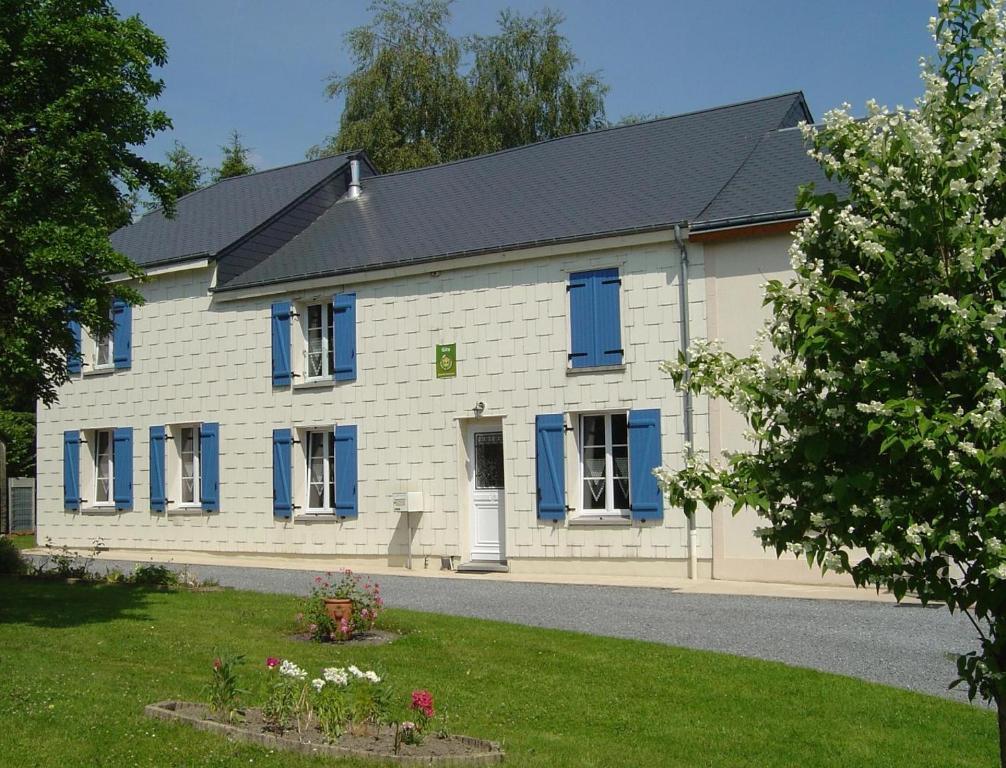 a large white house with blue windows and a yard at Le pre d'hyraumont in Rocroi