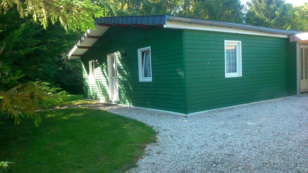 ein kleines grünes Gebäude mit einem Kieshof in der Unterkunft Le chalet du mazagran 