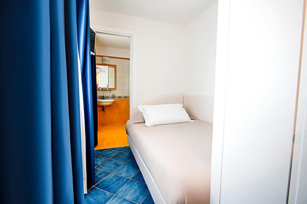 a bedroom with a white bed and blue curtains at Hotel Villa Pandora in Maiori