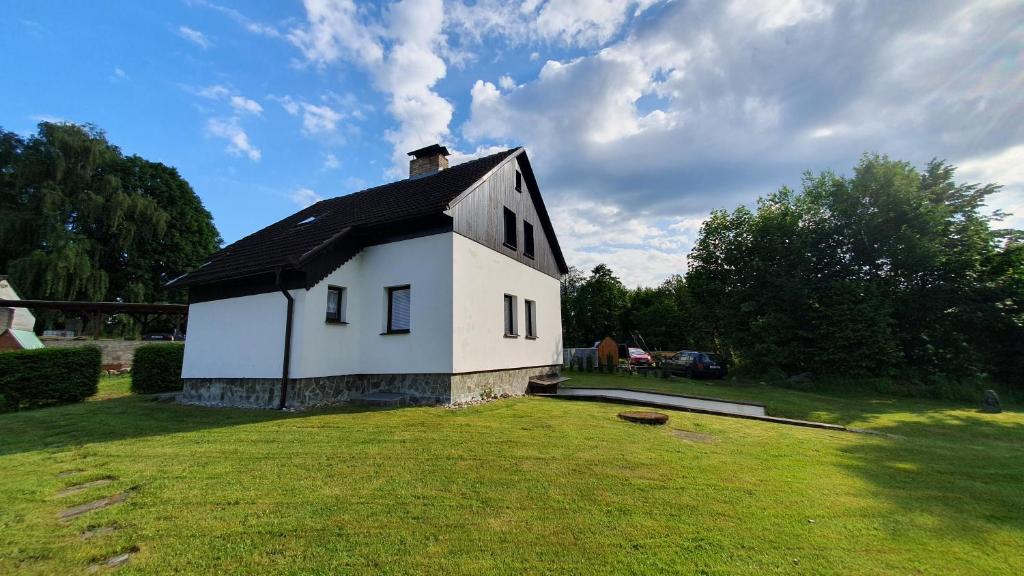 a small white house with a black roof in a yard at Hradiste Cottage in Nová Bystřice