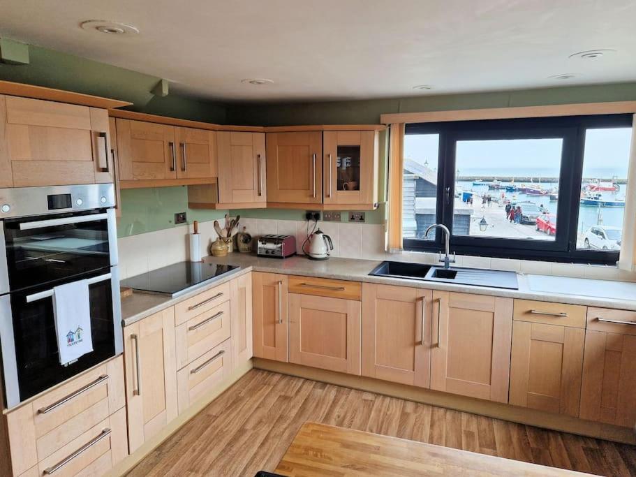 uma cozinha com armários de madeira e uma grande janela em Unique 2BD Apartment Folkestone Harbour em Kent