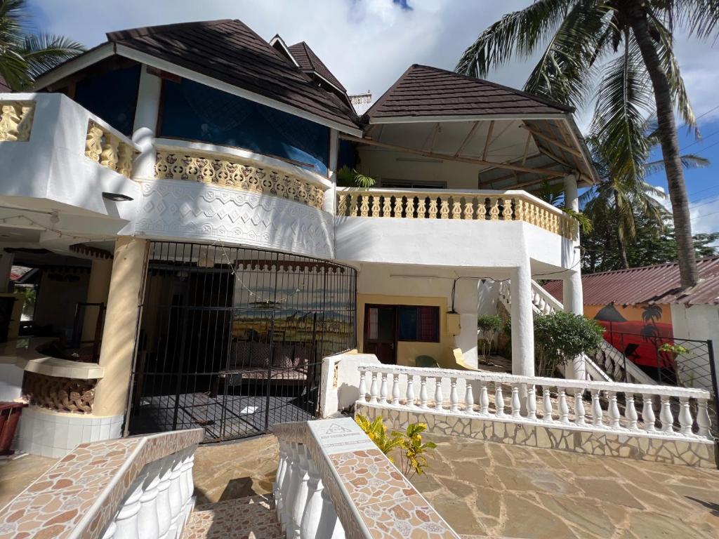 een wit huis met een poort en een balkon bij Charming and Remarkable 1 Bed Villa in Diani Beach in Diani Beach