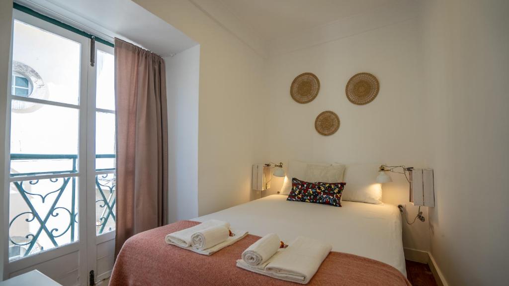 Dormitorio blanco con cama y ventana en The Alfama Apartment, en Lisboa