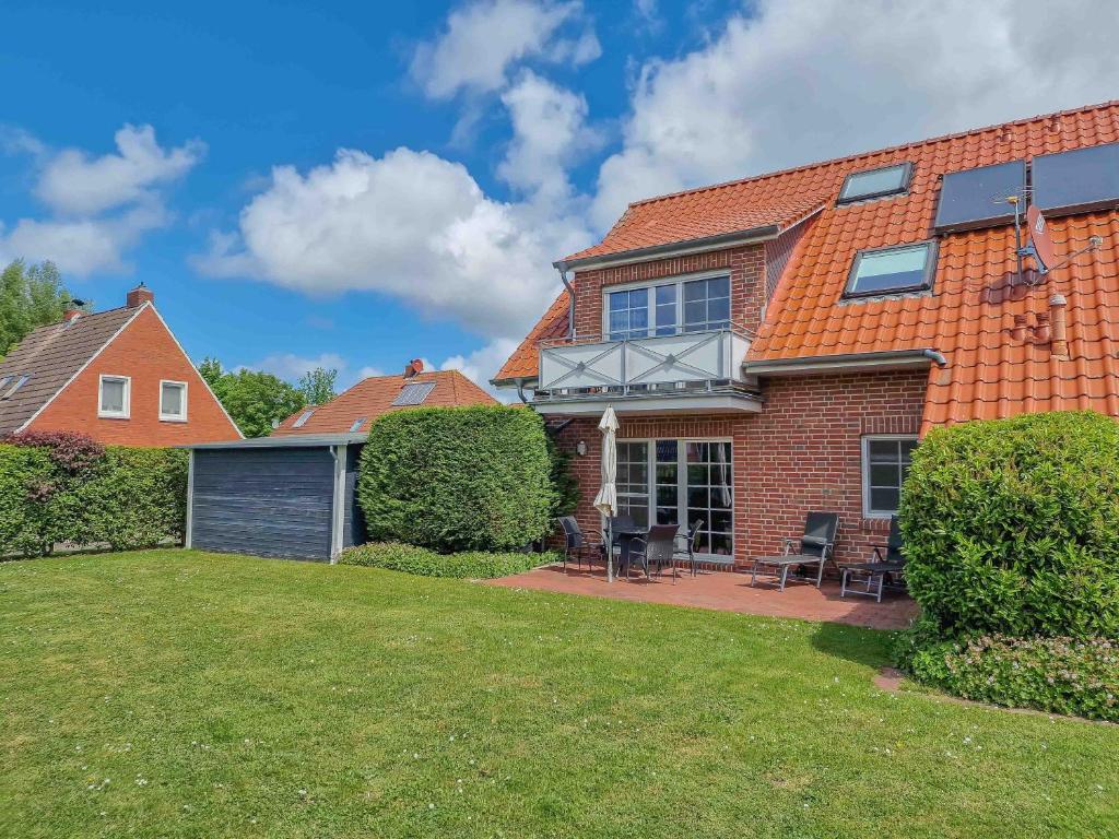 uma casa com um telhado laranja e um quintal em De Möhlenkieker 4 em Greetsiel