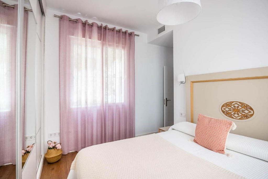 Schlafzimmer mit einem Bett und einem Fenster mit rosa Vorhängen in der Unterkunft Apartamento Leyendas de Becquer A4 in Sevilla