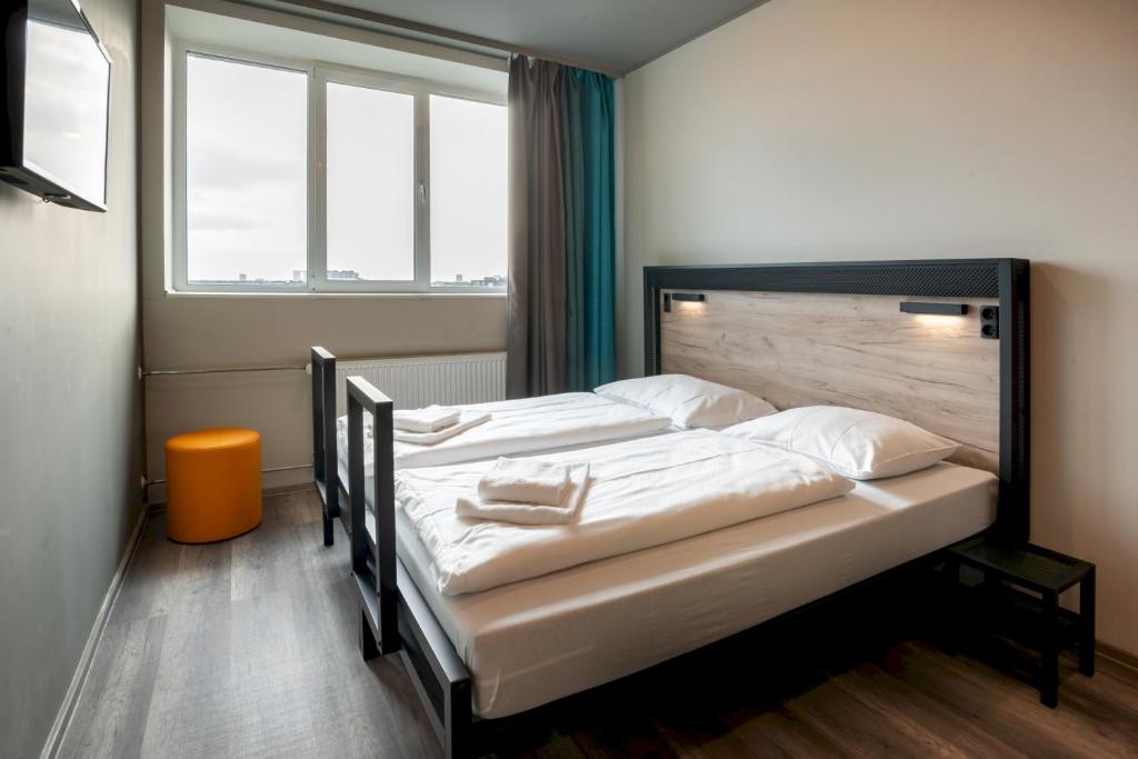 - une chambre avec un grand lit et des draps blancs dans l'établissement a&o Copenhagen Sydhavn, à Copenhague