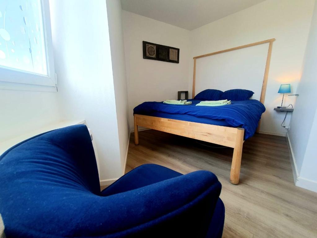 - une chambre avec un lit bleu et une chaise dans l'établissement Concept Appart'Hôtel - 201, à Saint-Brieuc