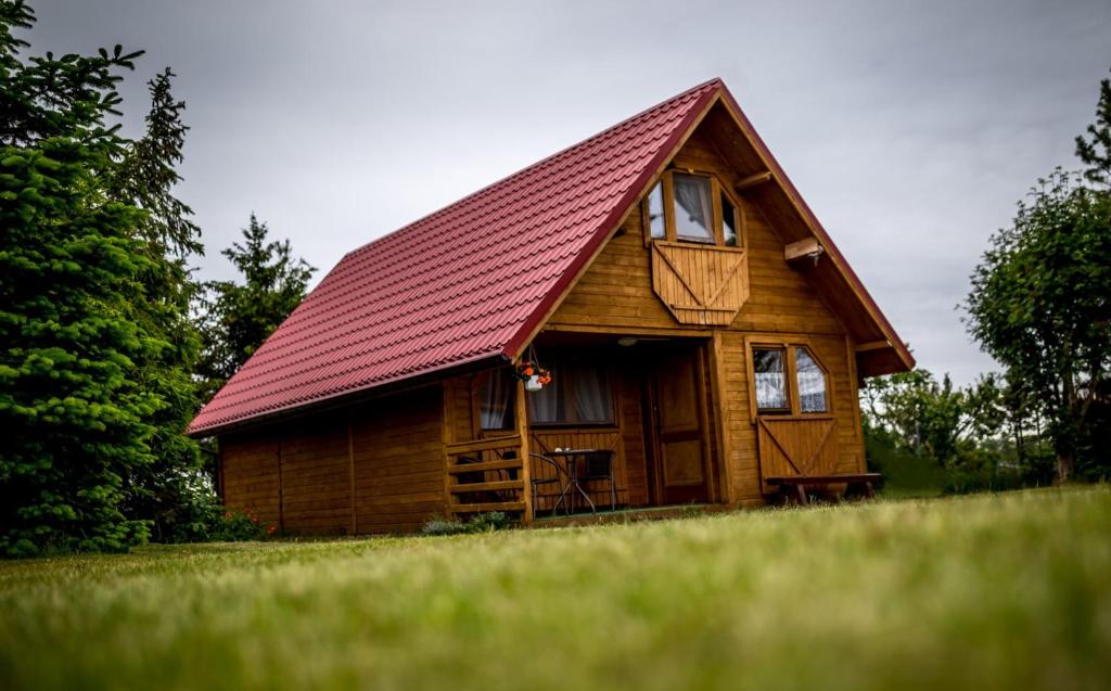 a small wooden cabin with a red roof at Villa Zastań in Międzywodzie