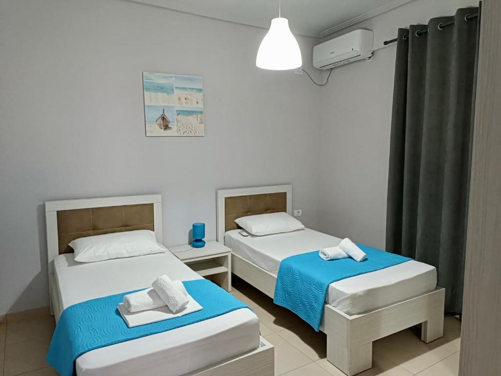 Habitación con 2 camas, lámpara y cortinas en AQUATIC Apartments Sarande, en Sarandë