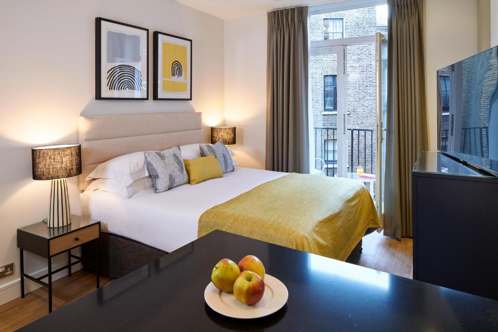 um quarto de hotel com uma cama e uma mesa com fruta em Cheval Harrington Court at South Kensington em Londres