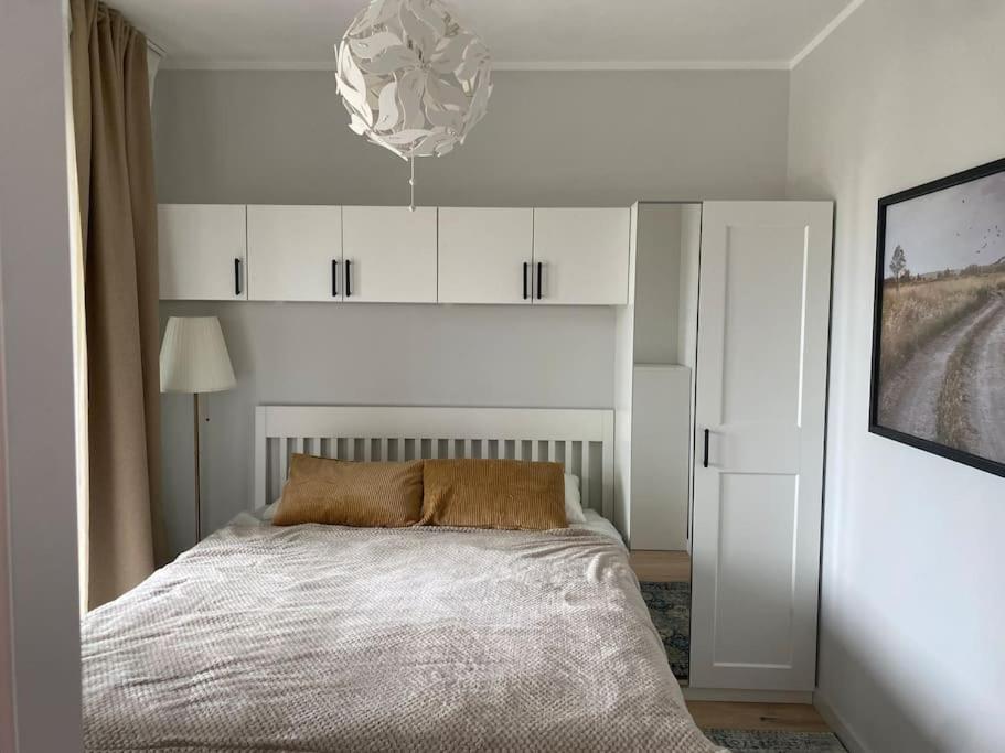 um quarto branco com uma cama e um lustre em Albatross_resort_alejaa em Ķesterciems