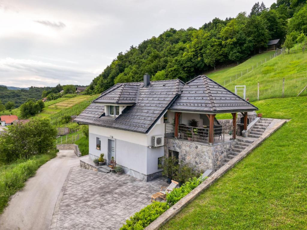 a white house with a slate roof on a hill at Vineyard cottage Jelenov hrib in Smarjeske Toplice