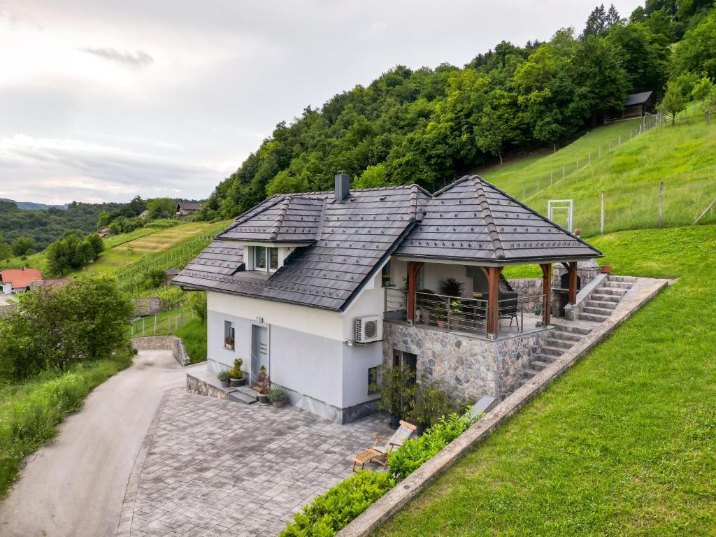 una casa blanca con techo de pizarra en una colina en Vineyard cottage Jelenov hrib, en Smarjeske Toplice