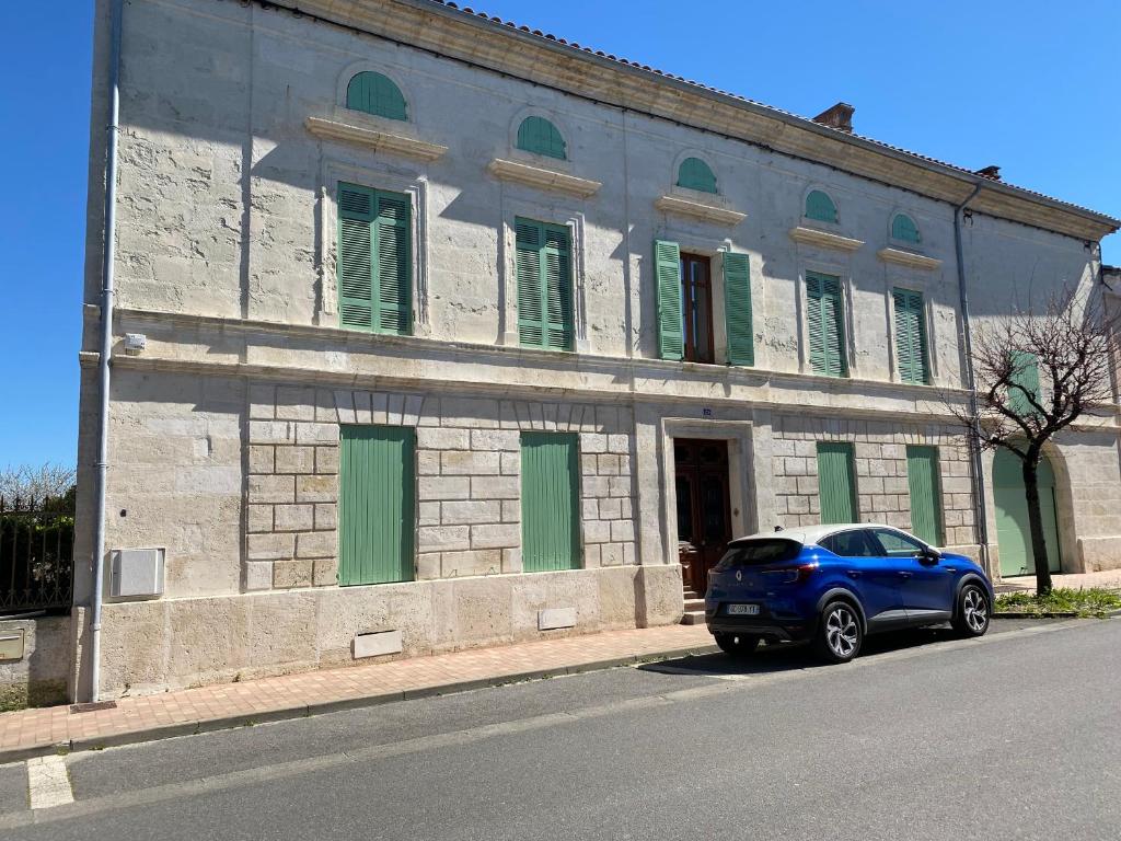 a blue car parked in front of a building with green shutters at The Little Robin in Chevanceaux