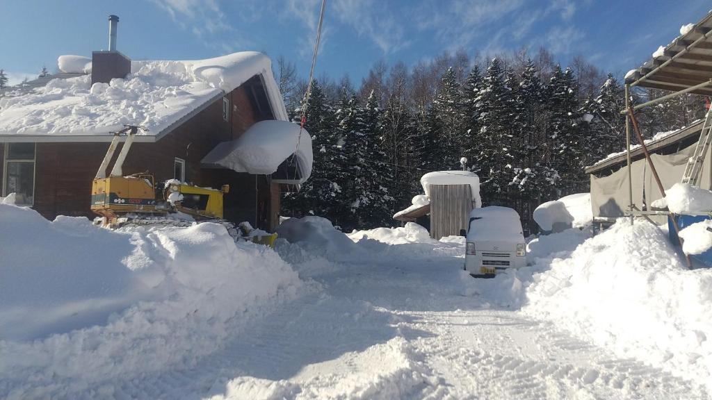 un patio cubierto de nieve con una casa y un camión en Ski base en Akaigawa