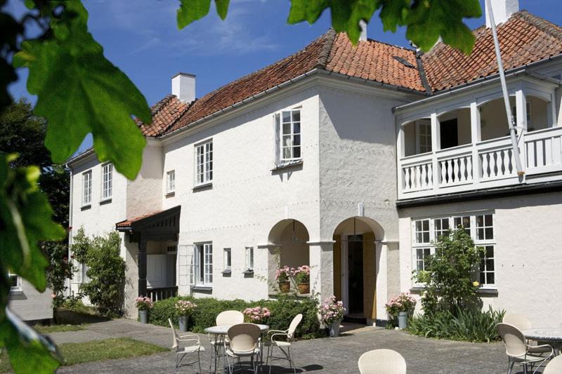 ein weißes Haus mit Stühlen und Tischen davor in der Unterkunft Villa Strand in Hornbæk