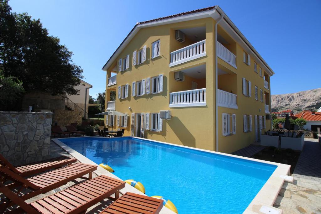 a building with a swimming pool in front of a building at Apartments Gorica 1 in Baška