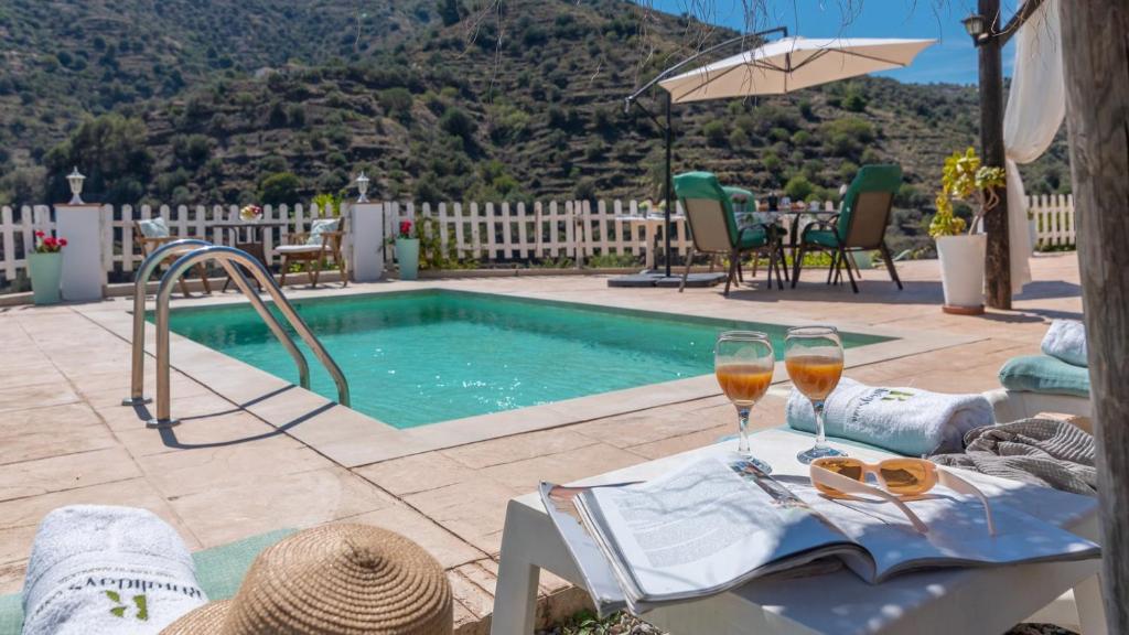 - une table avec deux verres de vin à côté de la piscine dans l'établissement Casa Campo de Ita by Ruralidays, à Torrox