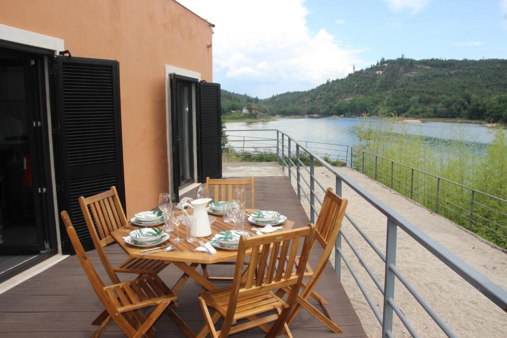 a table and chairs on a balcony with a view of a river at Casa do Rio in Treixedo