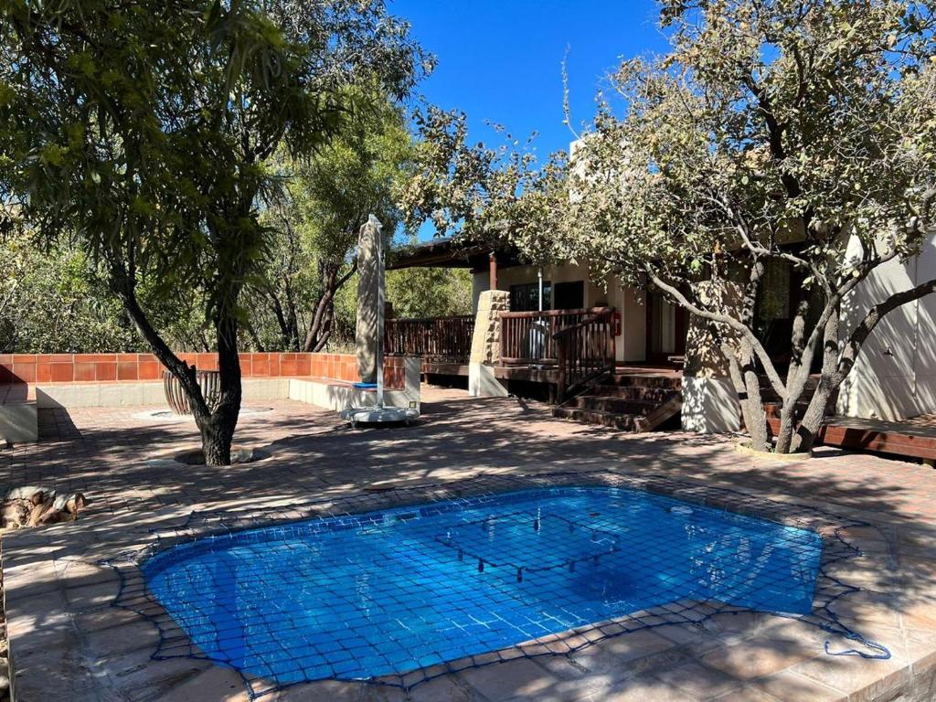 une piscine bleue dans une cour arborée dans l'établissement Elements Private Golf Reserve Unit 149 or 150, à Bela-Bela