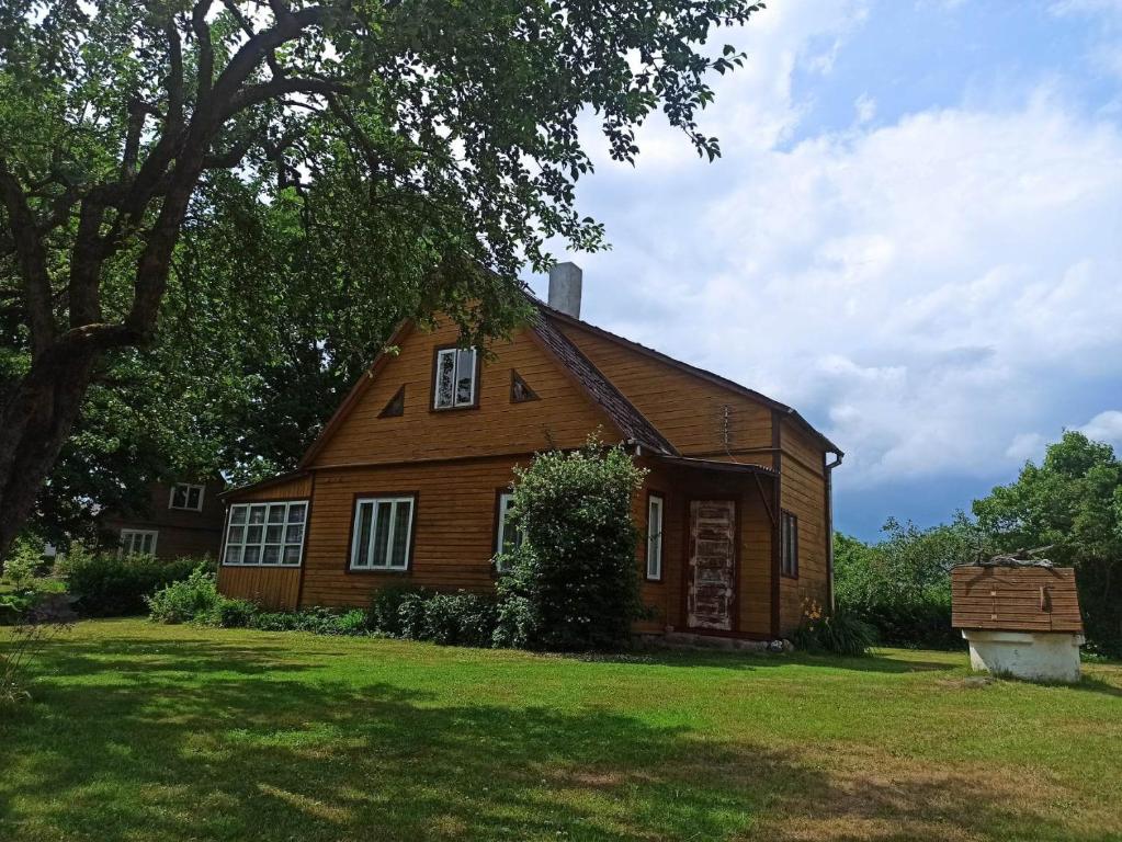 a large wooden house on a field with a tree at Vila Puriena in Kurtuvėnai