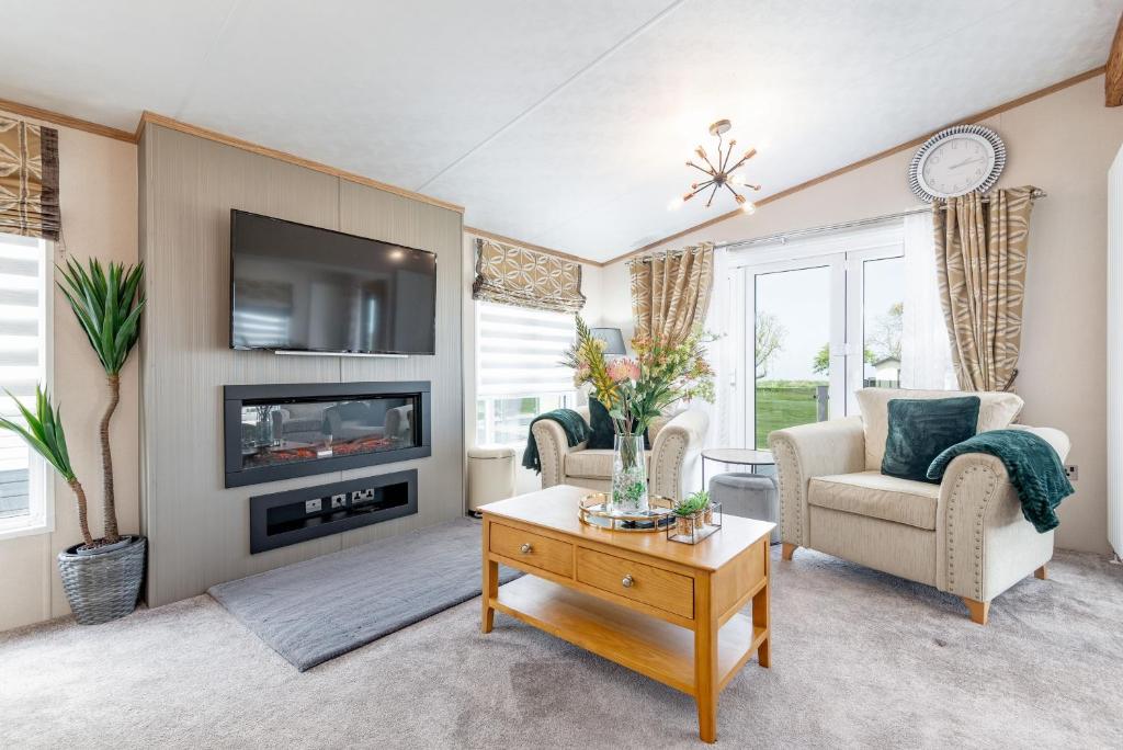 a living room with a fireplace and a tv at Stewarts Resort Lodge 76 in St Andrews