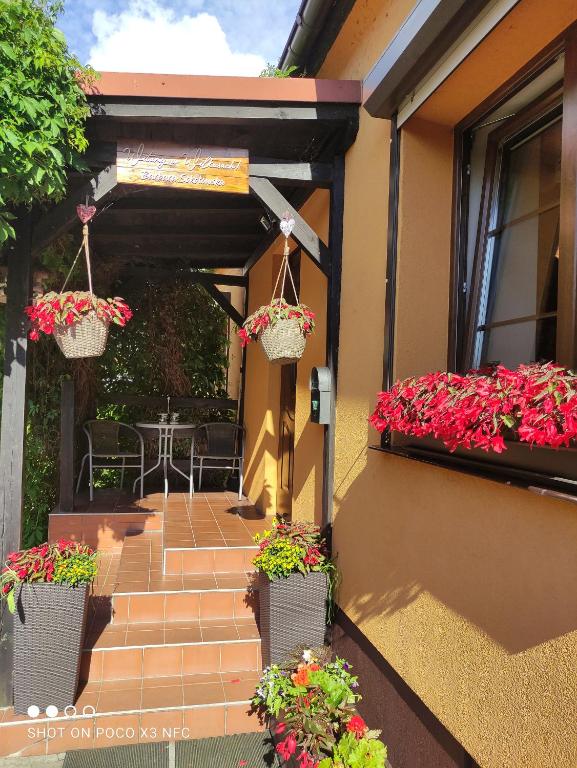 een patio met bloemen in manden op een huis bij Domek i pokoje Wilkasy in Wilkasy
