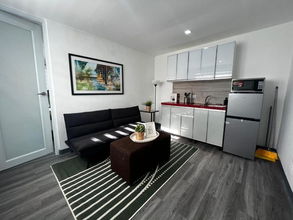 a living room with a black couch and a kitchen at Janer House at San Juan in San Juan