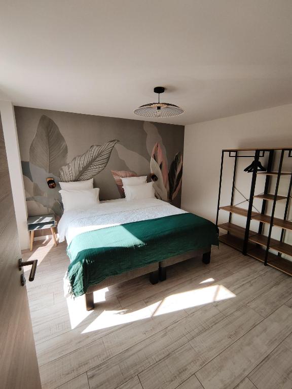 une chambre avec un grand lit avec une couverture verte dans l'établissement Gite du moulin brochat, à Saint-Jean-de-Vaux