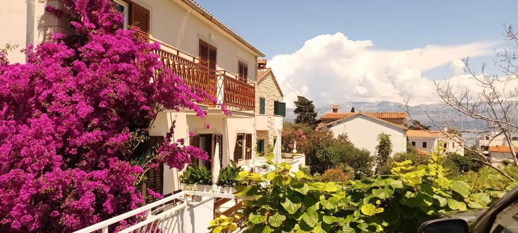 Una casa con flores púrpuras a un lado. en apartmani DIMIĆ, en Supetar