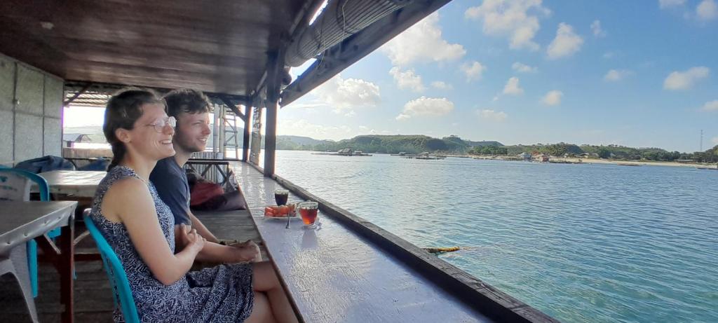 two people sitting on a boat on the water at Ekas beach floating room and restaurant in Ekas