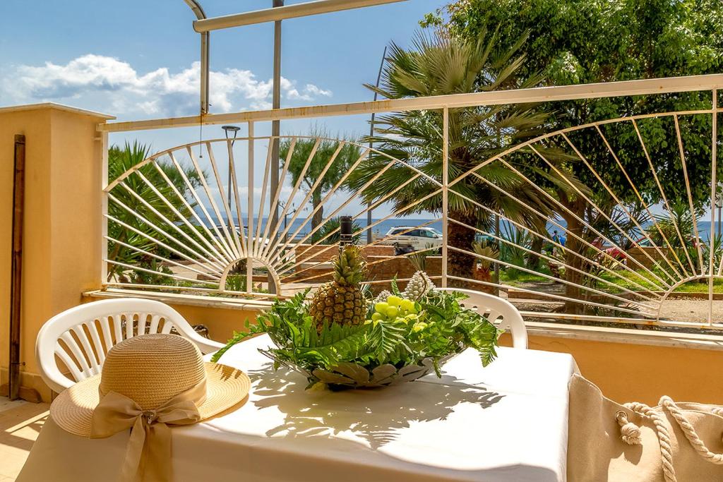 een tafel met een hoed en een kom ananas erop bij Casa Morgana-Beachfront in Roccalumera