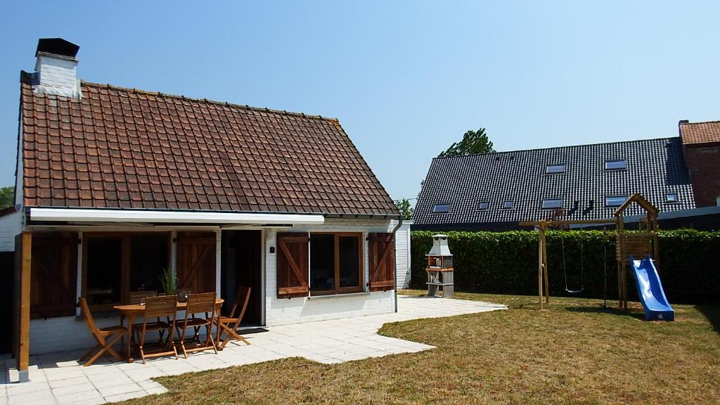 uma casa com uma mesa de madeira e um parque infantil em a l'aise aan zee em Koksijde