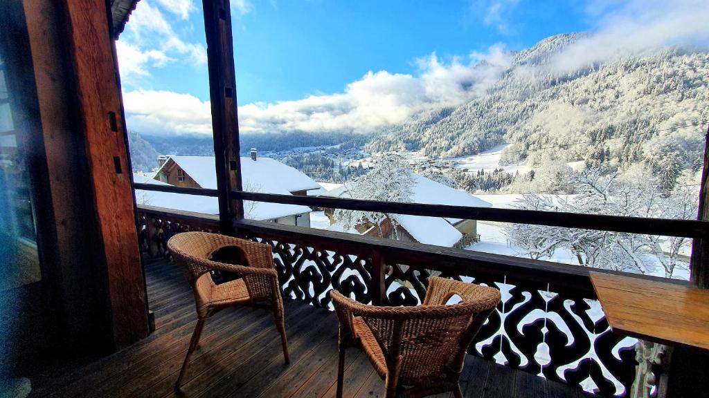 balcón con 2 sillas y vistas a una montaña nevada en Chalet Liberte en Saint-Jean-dʼAulps