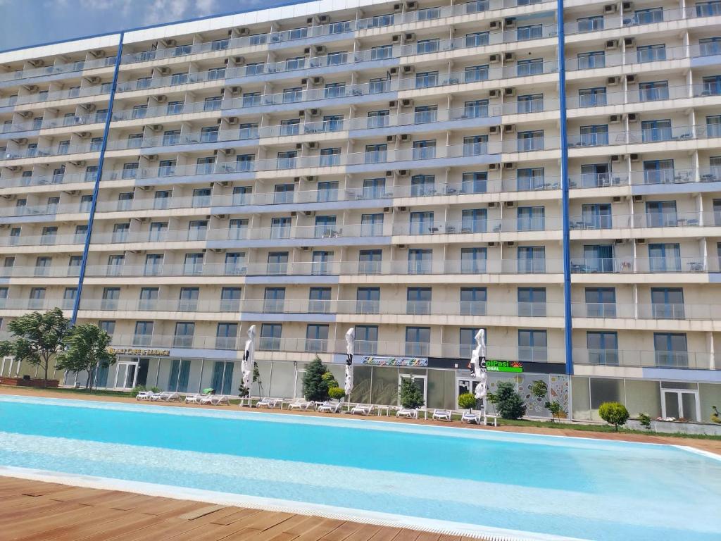 a large building with a swimming pool in front of it at Blaxy Resort STEFI in Douăzeci şi Trei August