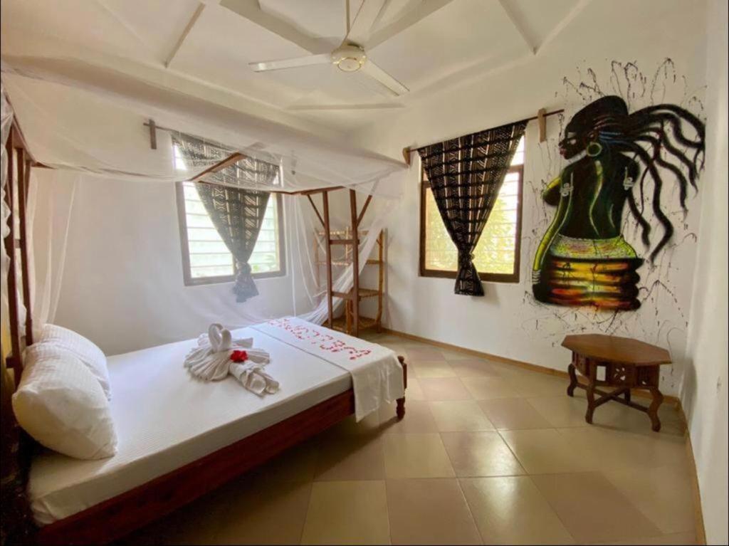 a bedroom with a bed and a painting on the wall at Wakanda Nungwi in Nungwi