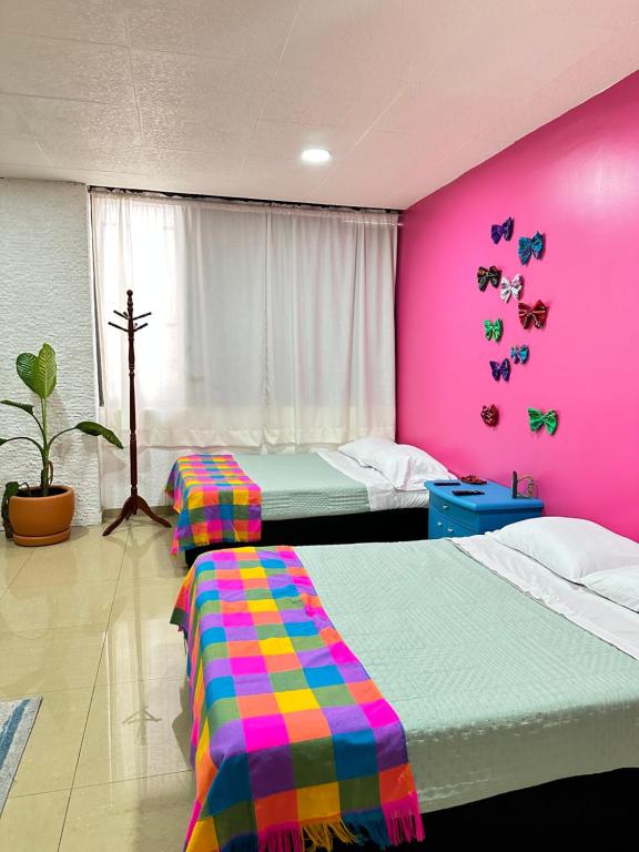 a bedroom with two beds and a pink wall at Rosa1B in Mexico City