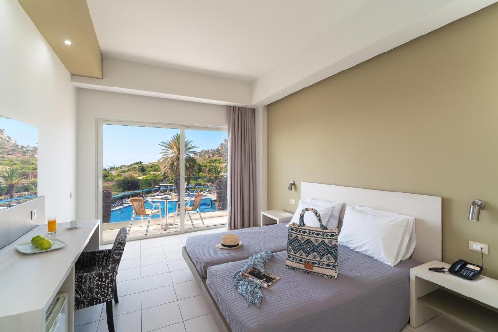 a bedroom with a bed and a view of a pool at Cathrin Hotel in Faliraki